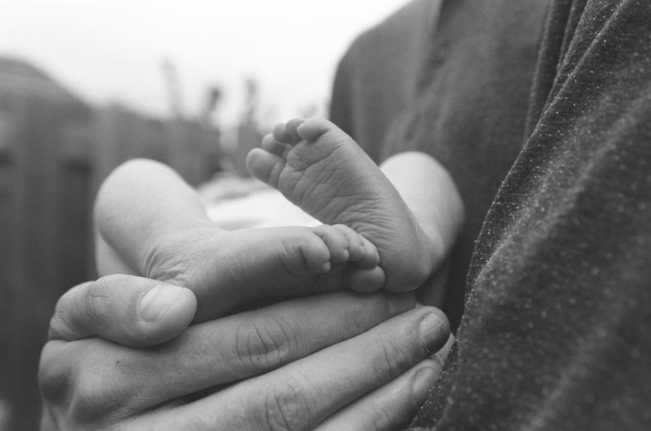 Ein Mann hält die Füße eines Babys in seinen Händen