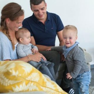 Un homme et une femme sont assis sur un canapé avec leurs deux enfants.