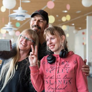 Deux parents et leur fille atteins de handicap se prennent en photo avec un smartphone