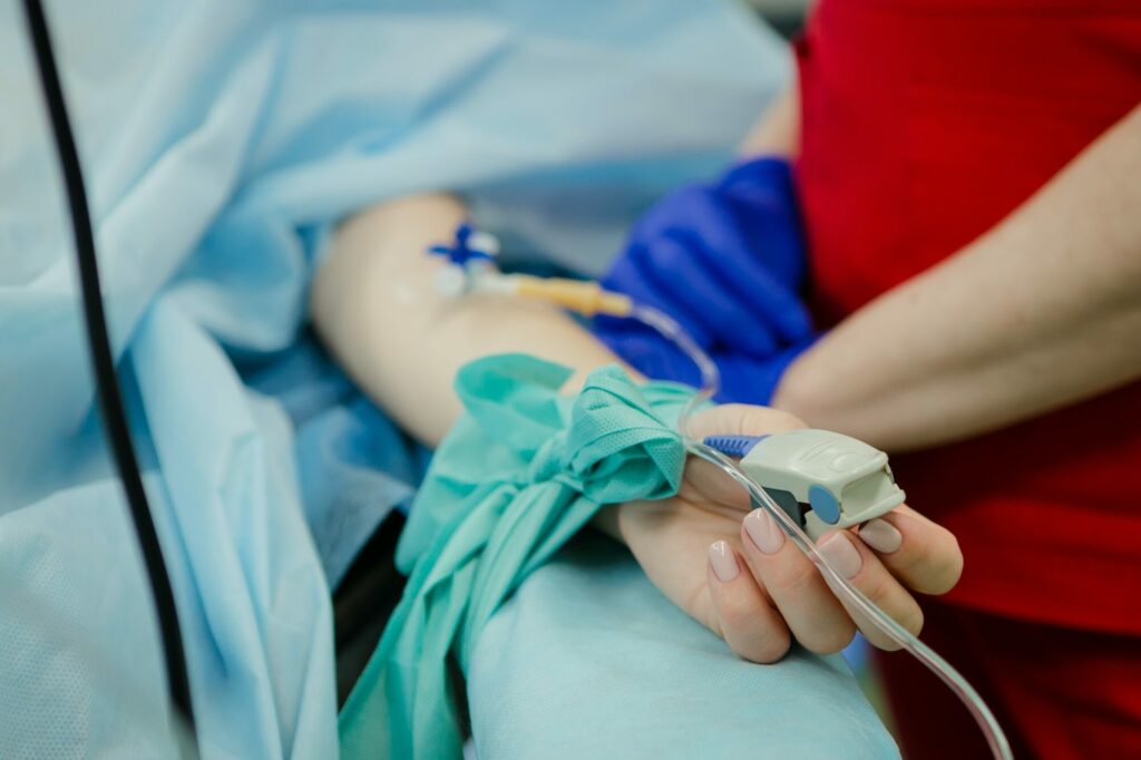 Une personne est allongée sur un lit d'hôpital, un oxymètre au doigt.