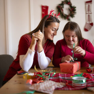 Two women wrapping a Christmas present together at home