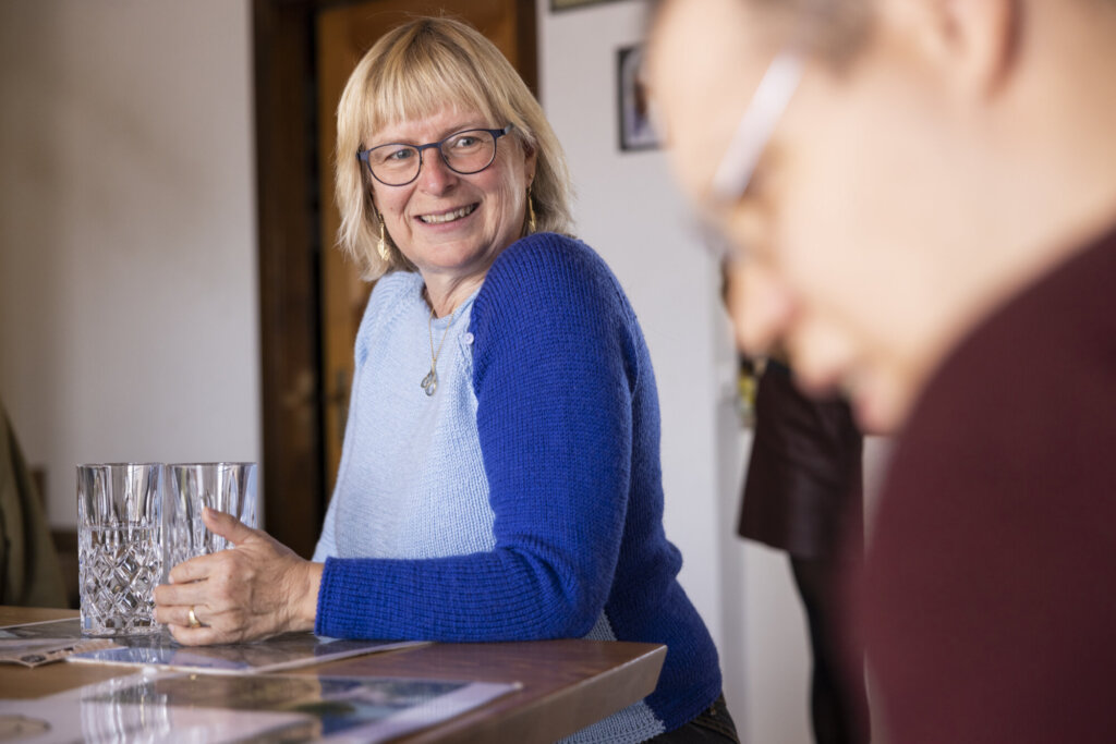 Eine Frau in Blau lächelt und schaut in Richtung eines Mannes (im Vordergrund, unscharf).